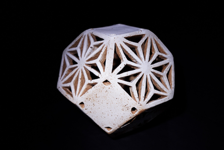 Honey Blocks — a faceted slab-built lamp pierced with a geometric honeycomb lattice, on black.