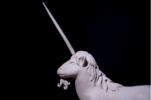 Detail of a ceramic unicorn sculpture — the horn and mane, unglazed, on black.