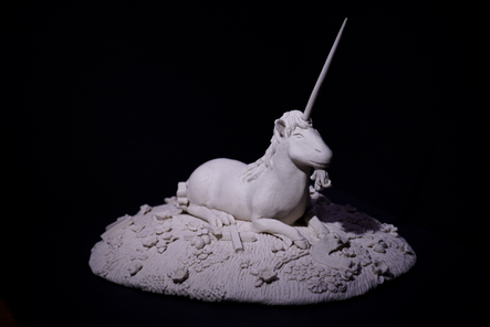 Unicorn out of Captivity — a reclining ceramic unicorn on a textured base, unglazed, on black.